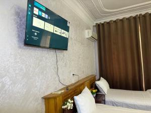 a room with two beds and a flat screen tv on the wall at BUKHARA Air Hostel in Bukhara