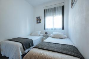 two beds in a room with white walls and a window at Apartamento Mairena in Mairena del Aljarafe +79 photos