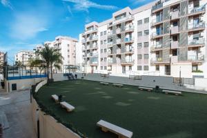 an artificial lawn in front of a building with benches at Apartamento Mairena in Mairena del Aljarafe