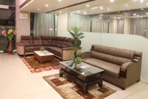 a living room with brown leather couches and a table at Veronica Hotel in Vadodara