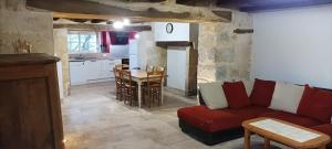 a living room with a red couch and a kitchen at Charme et tranquillité au cœur du Périgord in La Rafigne