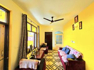 a living room with a couch and a ceiling fan at Kolaveri Homes in Bīr