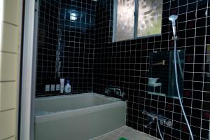 a black tiled bathroom with a tub and a shower at 一棟貸しの宿 Granny and the sea グラニーアンドザシー in Shima +63 photos