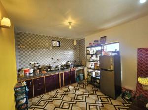 a kitchen with a refrigerator and a tiled floor at Kolaveri Homes in Bīr