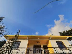 a yellow and white house with a yellow roof at Kolaveri Homes in Bīr