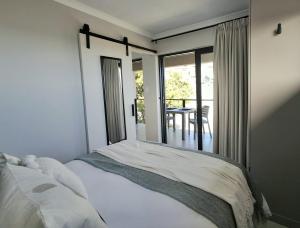 a bedroom with a bed with a view of a patio at 9 at Sea in Great Brak River