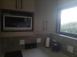 a kitchen with a microwave and a window at 9 at Sea in Great Brak River +19 photos