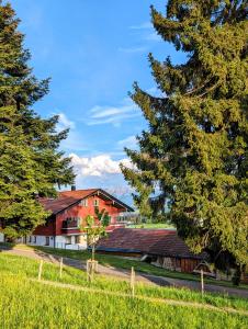 a barn with trees in front of a house at Ferienwohnung Alpenblick Dorner - VON MARTIN in Oberreute