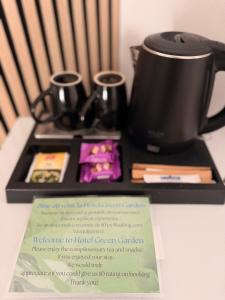a table with a coffee pot and two cups on it at Hotel Green Garden in Bucharest