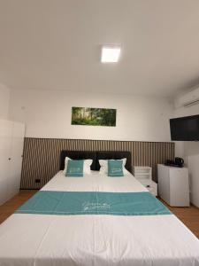 a bedroom with a large white bed with blue pillows at Hotel Green Garden in Bucharest