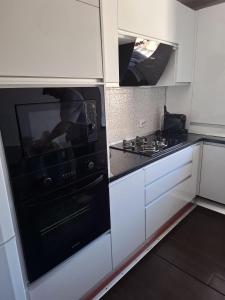 a kitchen with a black oven and white cabinets at B&B Apartment in Petroşani +11 photos