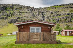 a small cabin with a fence in front of a mountain at Guesthouse Skálafell in Skálafell