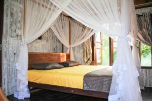 a bedroom with a canopy bed with curtains at Matara Eco Friendly Treehouse in Matara