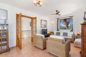 a living room with wicker furniture and a tv at Villa Sea Garden Holidays by 3VILLAS in Port d'Addaia