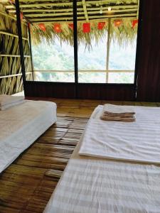 two beds in a room with a large window at Puluongholiday homestay2 in Làng Chiêu