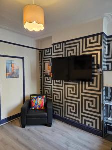 a living room with a couch and a television on a wall at Ince House in Liverpool