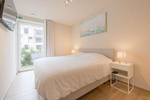 a bedroom with a white bed and a window at The Captainhouse in Nieuwpoort