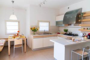 a kitchen with white cabinets and a table with chairs at Villa Fiore in Novilara