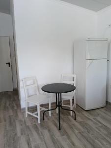 a table and two chairs and a refrigerator in a room at Estúdio ensolarado in Fernao Ferro +3 photos