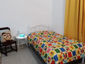 a bedroom with a bed with a colorful comforter at Estúdio ensolarado in Fernao Ferro