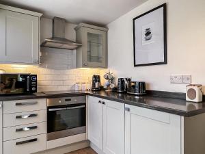 a kitchen with white cabinets and a black counter top at Cygnet Cottage in Warkworth
