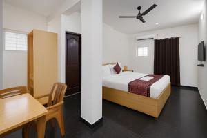 a bedroom with a bed and a table and a desk at Mysore Couple Friendly at 999 in Mysore