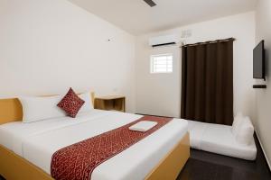 a bedroom with a large white bed and a television at Mysore Couple Friendly at 999 in Mysore