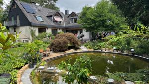 a house with a pond in front of a garden at FeWo-Tannenriede in Braunschweig