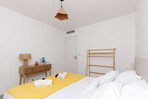 a white bedroom with a bed and a table at Féeries Provençales YourHostHelper in Grimaud
