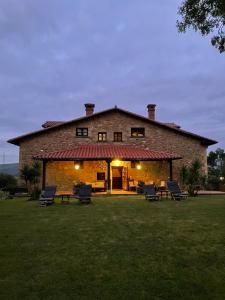 a large brick house with chairs in the yard at Posada Rural Valoria in Valoria
