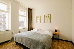a bedroom with a bed and two windows at Bloemendaal Hotel Collection Apartments in Bloemendaal