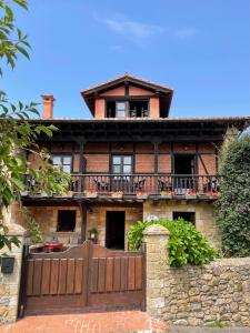 a brick house with a wooden fence in front of it at Posada Rural Valoria in Valoria