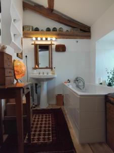a bathroom with a sink and a tub and a mirror at La chambre du lac in Meaux-la-Montagne