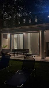 two chairs and a bench in a yard at night at Blue Breeze in Paralia Vrachou