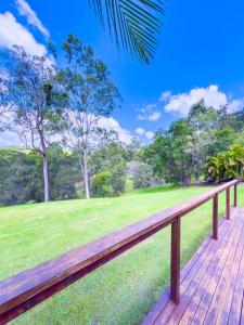 a wooden deck with a green field and trees at Solis Acreage Escape in Advancetown