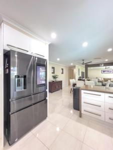 a kitchen with a stainless steel refrigerator and a living room at Solis Acreage Escape in Advancetown