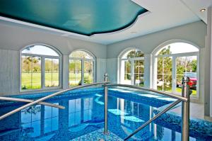 a swimming pool in a house with windows at Xavin Wellness Hotel & Restaurant in Harkány