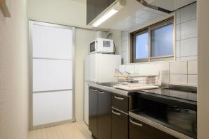 a kitchen with a sink and a microwave at Wilshire APT ホテル in Miyazaki