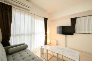 a living room with a couch and a table and a television at Wilshire APT ホテル in Miyazaki