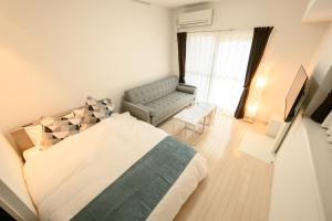 a bedroom with a bed and a couch and a chair at Wilshire APT ホテル in Miyazaki