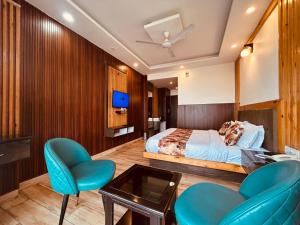 a bedroom with a bed and two chairs and a tv at Sawer Fan Resort in Mussoorie