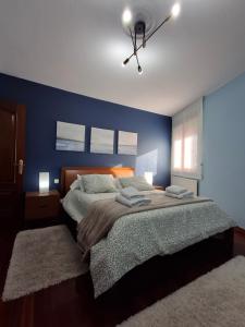 a bedroom with a large bed with a blue wall at As Pitas 1 in Tapia de Casariego