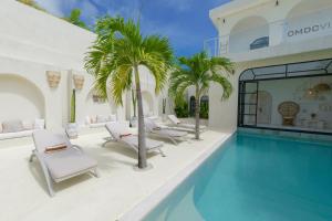 a pool with chairs and palm trees next to a building at 5BR Ocen View Villa in Jimbaran in Jimbaran
