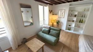 a living room with a green chair and a mirror at Le Duplex du Pont in Auxerre