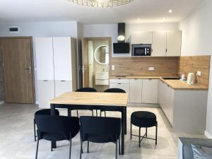 a kitchen with a table and chairs in a room at Apartamenty przy Starym Basenie in Sobótka