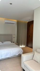 a bedroom with a white bed and a couch at Malath Farm in Al Rahba