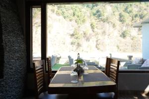 a table in a room with a large window at Bel-La Monde Riverside Jim Corbett - "A Unit of Luxe Opera Hotels & Resorts" in Garjia
