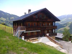 a large wooden house on a hill with mountains at Bauernhaus Fankhauser in Hippach