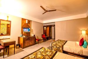a hotel room with a bed and a television at Tangerine Boutique Resort in Calangute