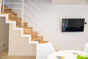 a living room with a staircase with a flat screen tv at Cefalù Beach Garden House in Cefalù +10 photos